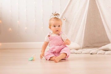 Naklejka premium baby girl in the nursery playing,bright children's room, textiles for children's room