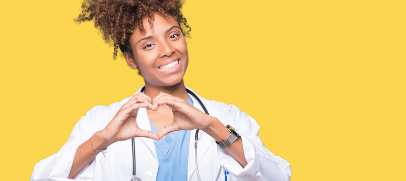 Young african american doctor woman over isolated background smiling in love showing heart symbol and shape with hands. Romantic concept.