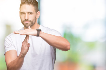 Handsome man wearing white t-shirt over outdoors background Doing time out gesture with hands,...