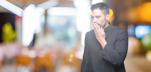 Young Christian priest over isolated background bored yawning tired covering mouth with hand....