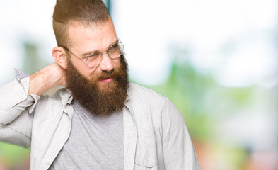 Obraz premium Young blond man wearing glasses Suffering of neck ache injury, touching neck with hand, muscular pain