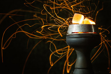  red-hot coals lie on a bowl of a hookah and sparks fly from them in different directions. on a black background