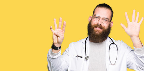 Young blond doctor man with beard wearing medical coat showing and pointing up with fingers number...