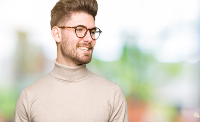 Young handsome business man wearing glasses looking away to side with smile on face, natural expression. Laughing confident.