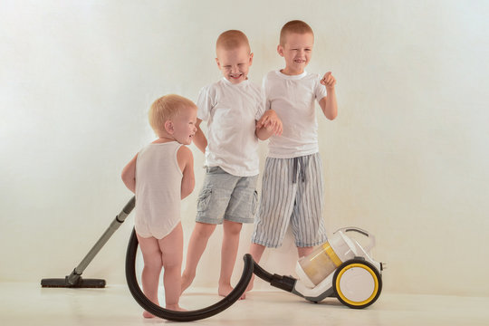 Caucasian blond brothers do the cleaning in their room. White isolated background, interior.