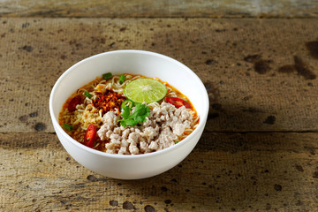 Spicy instant noodles soup with minced pork (tom yum moo sub) on wood table