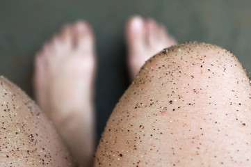 Caucasian white leg doing natural scrub with sugar and coffee grounds to fight folliculitis, personal care concept