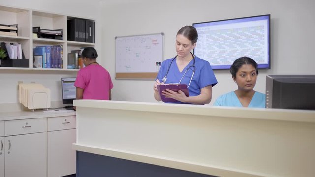 Three nurses working at nursing station, camera moves left then right