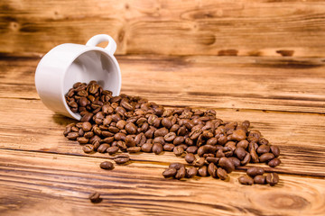 White cup and scattered coffee beans on wooden table