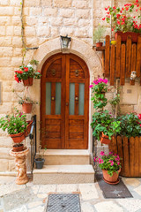 Fototapeta na wymiar Italy, Apulia, Metropolitan City of Bari, Bari. Wooden doors and potted flowers on a stone building.