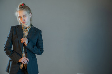 Fototapeta premium beautiful blonde with blue eyes in business trouser suit posing in front of camera. Young woman actress actively expresses her emotions and touches her hair