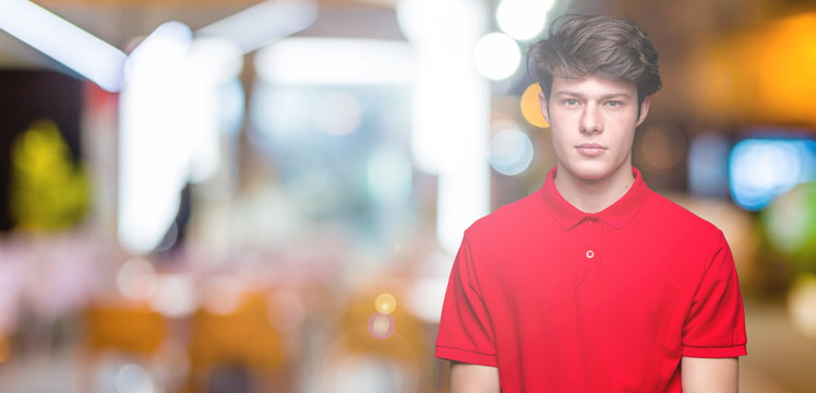 Young handsome man wearing red t-shirt over isolated background Relaxed with serious expression on face. Simple and natural looking at the camera.