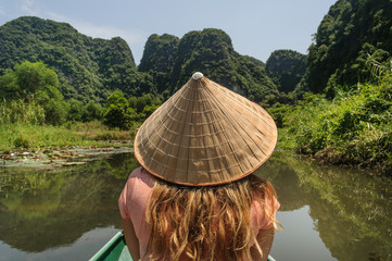 Una turista de pelo largo rubio de espaldas en bote tour por el Valle de Tam Coc,Vietnam