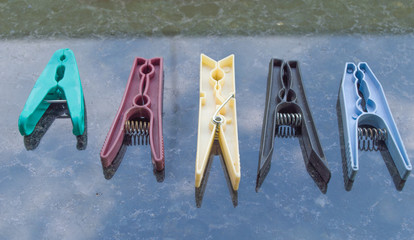 five clothespins in different colors used to put clothes on clothesline, diversity concept