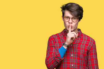 Young handsome man wearing glasses over isolated background asking to be quiet with finger on lips....