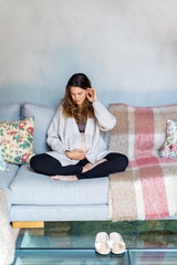 Obraz premium Pregnant woman sitting on a sofa and caressing her belly