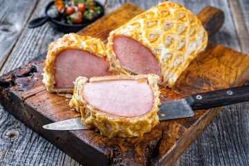 Traditionell gebackenes Kasseler Schweinerücken Steak am Stück und aufgeschnitten in Blätterzeig...
