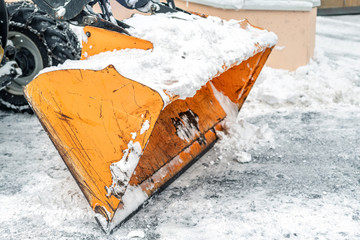 Close-up snowplow of big tractor machine removing and cleaning snow after storm on icy road or city...