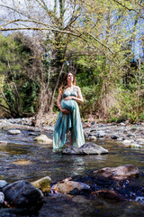 Fototapeta premium Pregnant girl posing near the river wearing a green dress.