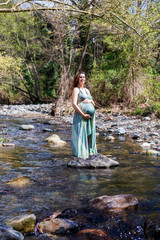 Pregnant girl posing near the river wearing a green dress.