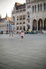 Obraz premium dad and little daughter are walking in the square near the Hungarian Parliament 1