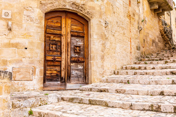 Italy, Basilicata, Province of Matera, Matera. Old wooden door in a stone wall above stone steps.