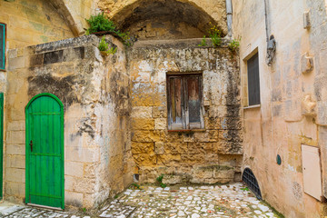 Italy, Basilicata, Province of Matera, Matera. Old stone building with wooden shutters and a green door.