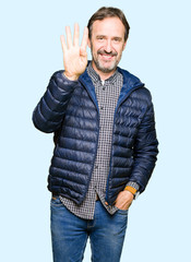 Middle age handsome man wearing winter coat showing and pointing up with fingers number four while smiling confident and happy.