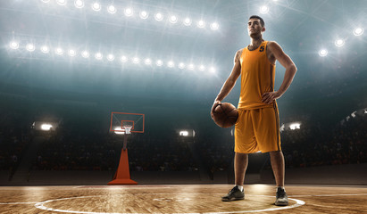 Fototapeta premium Young professional basketball player in sports uniform on a court with a ball. Floodlit sports arena