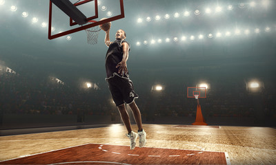 African american basketball player in action on a floodlit court. Slam dunk  © TandemBranding