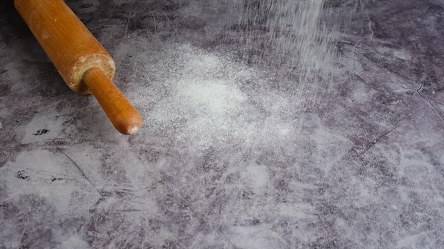 Close-up rolling pin and white flour on a gray background. Bake menu, recipe, homemade pastry concept.