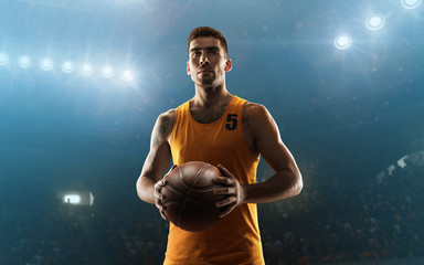 Young professional basketball player in sports uniform on a court with a ball. Floodlit sports arena