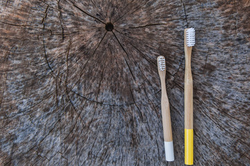 Two eco friendly bamboo wooden toothbrushes on wooden background. Copy space, flat lay.