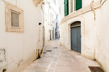 Italy, Apulia, Province of Taranto, Martina Franca. Narrow, curving street lined with white stucco buildings.