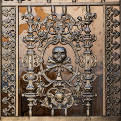 Italy, Apulia, Metropolitan City of Bari, Locorotondo. May 30, 2019. Skull and bones in the ironwork gate to a mausoleum in the local cemetery.