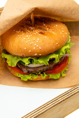 Craft beef burgers with vegetables. Delicious fresh homemade burger. Tasty juicy and beautiful burger on a paper bag