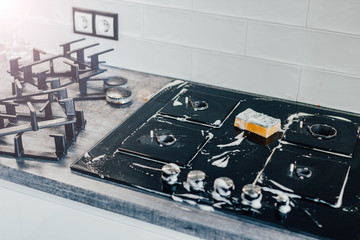 cleaning the kitchen, cleaning a modern gas stove with a sponge and foam.