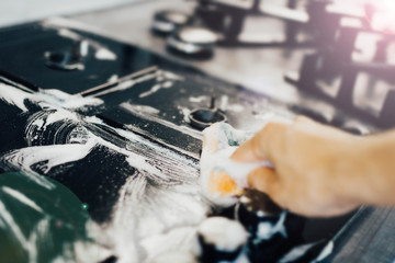 cleaning the kitchen, cleaning a modern gas stove with a sponge and foam.