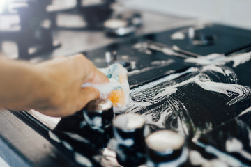 cleaning the kitchen, cleaning a modern gas stove with a sponge and foam.