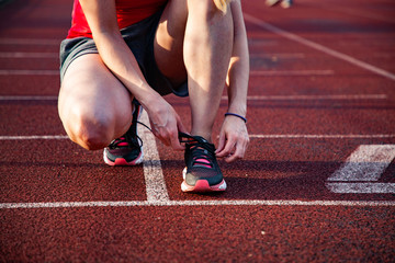 young woman on running track lacing her shoes