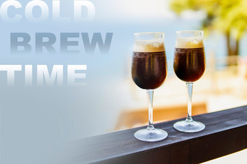 Cold brew coffee espresso in transparent glass with blurred sea side background. Relax summer time concept. cold refreshing drink idea.