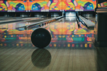Vintage filter used on bowling ball in focus with blurred view down bowling alley with gutter guards in place 