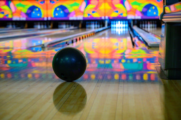 Bowling ball in focus with blurred view down bowling alley with gutter guards in place 