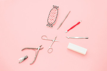 Manicure concept set on pink background. Tools for perfect nails, polishing nail buff, cuticle pusher, cuticle trimmer, nail file, nail scissors, toes separator, nail clippers, toenail clippers.