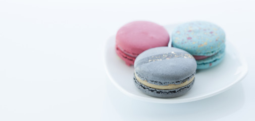 Macaroons on a white saucer and a light background. Space for text