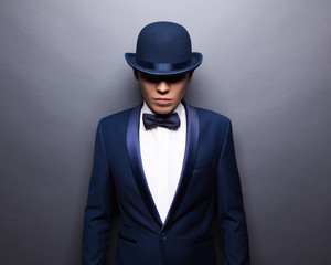 Portrait of handsome stylish man in elegant gray suit and bowler hat.