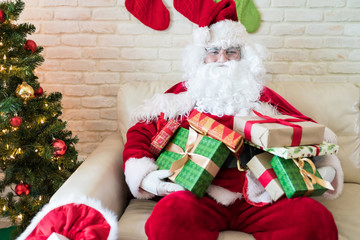 Santa Claus with gifts on sofa during Merry Christmas