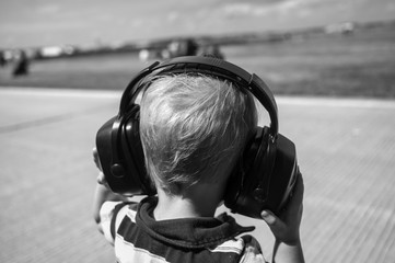 black and white picture of a Caucasian child wearing hearing protection at an airshow