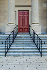 Stairs with railing leading to red doors.