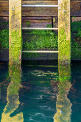 Steps on a wharf leading to the ocean with the steps reflecting in the water.